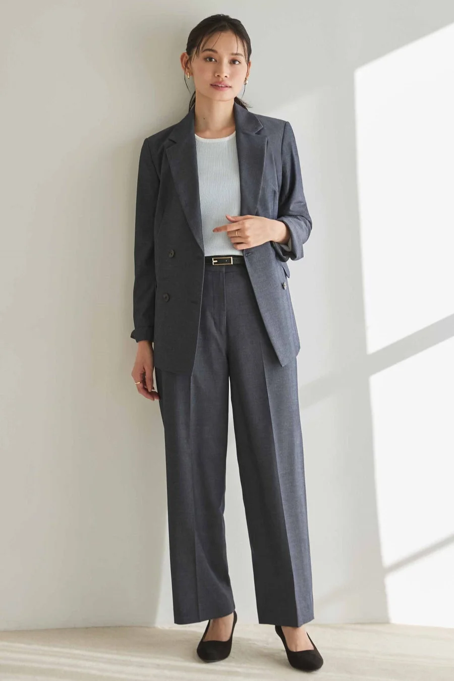 チャコールグレーのパンツスーツを着た女性