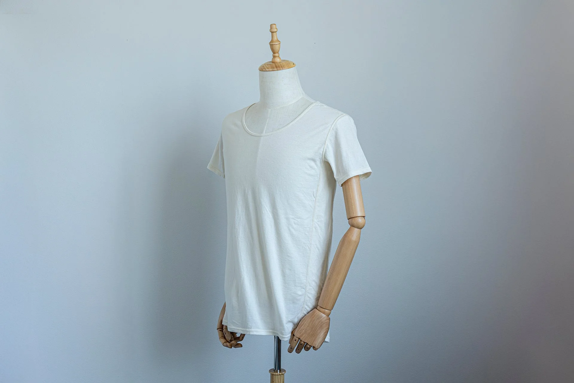 木製のマネキンに着せられたシンプルな白い半袖Tシャツ