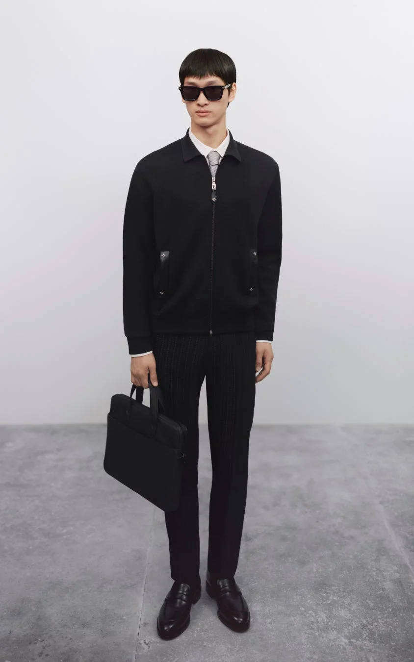 黒いジップアップジャケットとスラックスを着用した男性