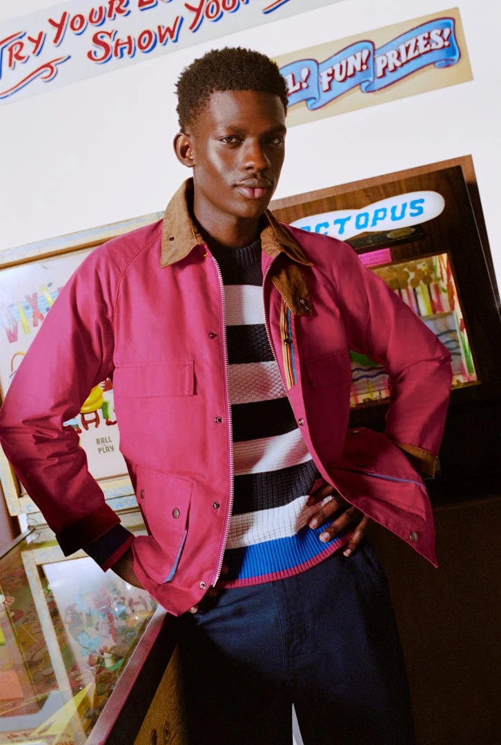 ピンクのジャケットとストライプのセーターを着た男性