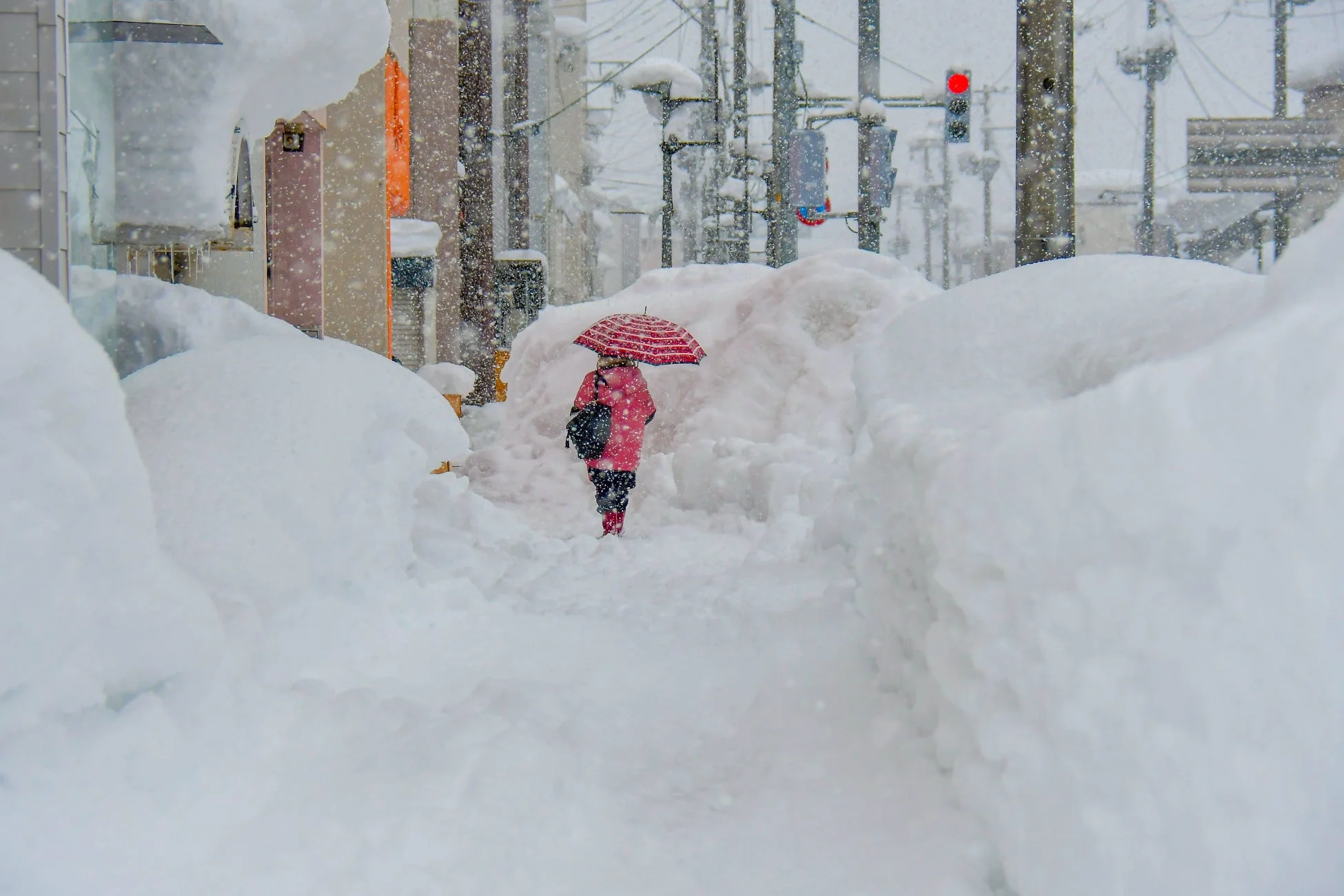 雪が降り積もる街中を歩く人