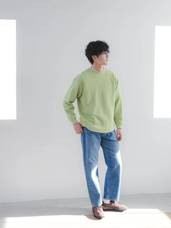 ライトグリーンのスウェットとデニムパンツを着用した男性