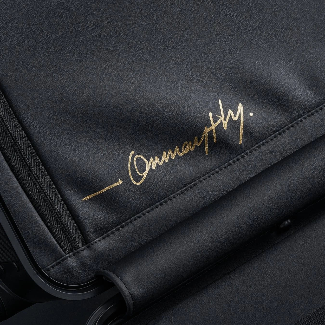 黒い革のような素材に金色の手書き風ロゴ「- Onmaythy.」がデザインされた製品の一部をクローズアップした画像です