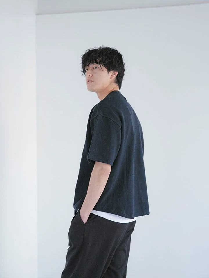 黒いTシャツと白いインナーを重ね着した若い男性