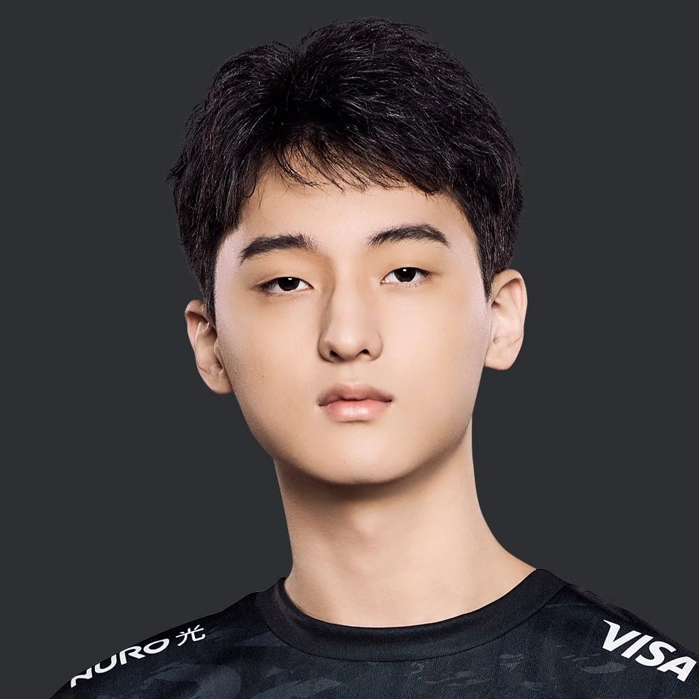 黒いシャツを着た若いアジア人男性のバストアップポートレート。真顔でカメラを見つめており、シャツには「NURO光」と「VISA」のロゴが見える。eスポーツ選手かゲーマーの可能性が高い。