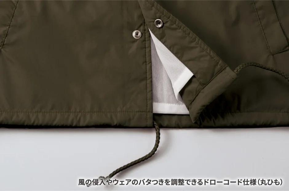 カーキ色のジャケットの裾部分をクローズアップした画像です。風の侵入やウェアのバタつきを調整できるドローコード（丸ひも）が特徴で、機能的なデザインが示されています。
