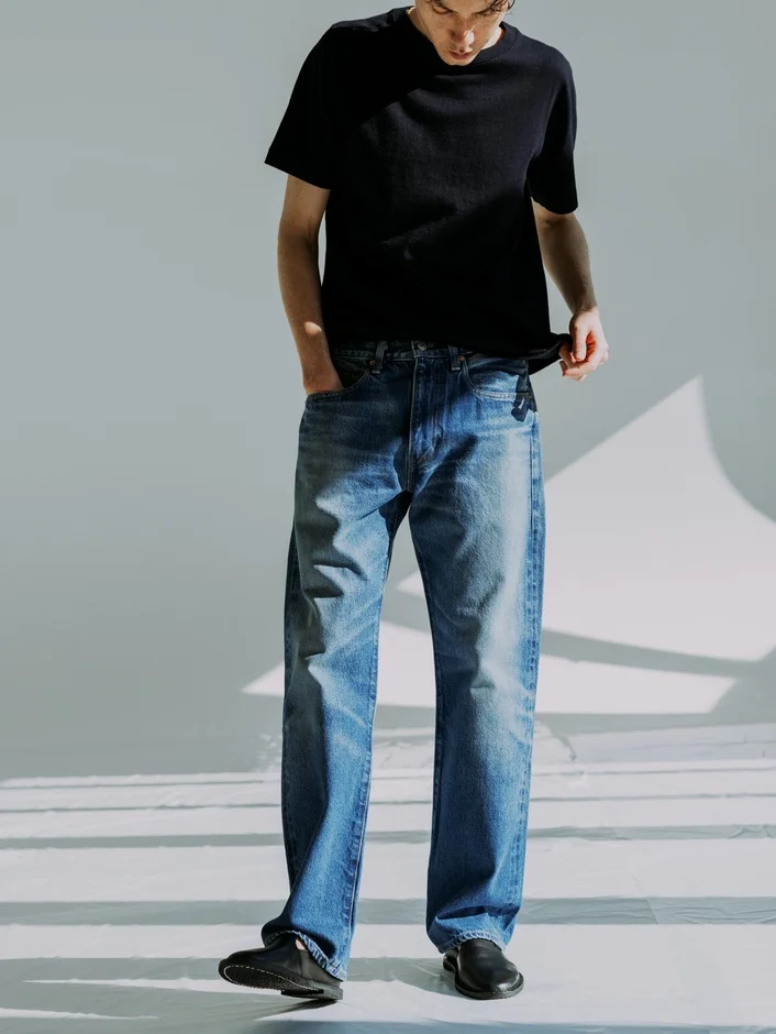 黒のTシャツとブルーデニムを着用した男性