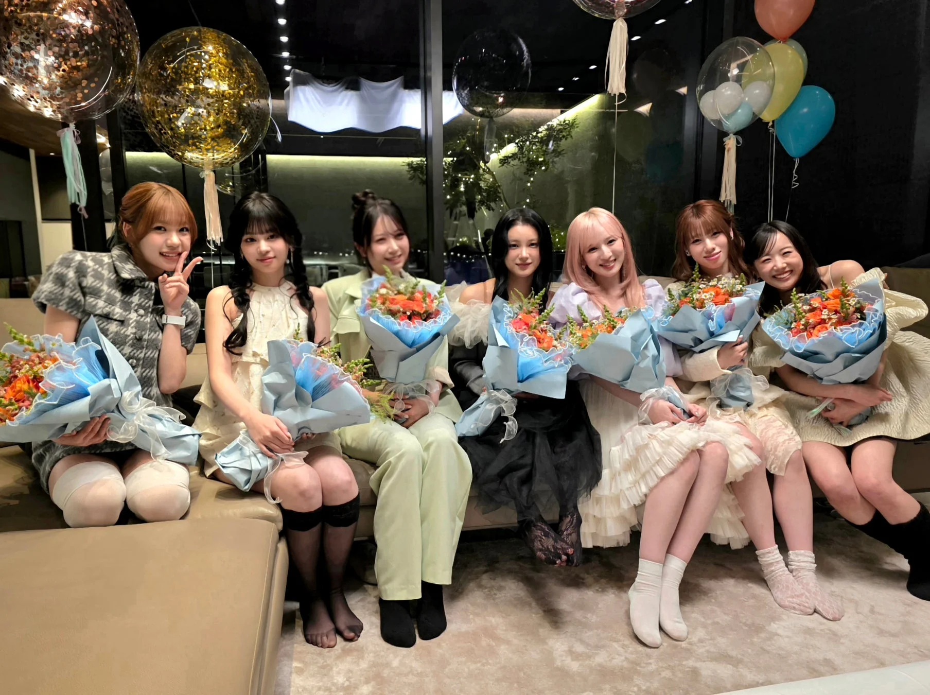 7人の女性が花束を持ち、笑顔でカメラにポーズをとっている集合写真です