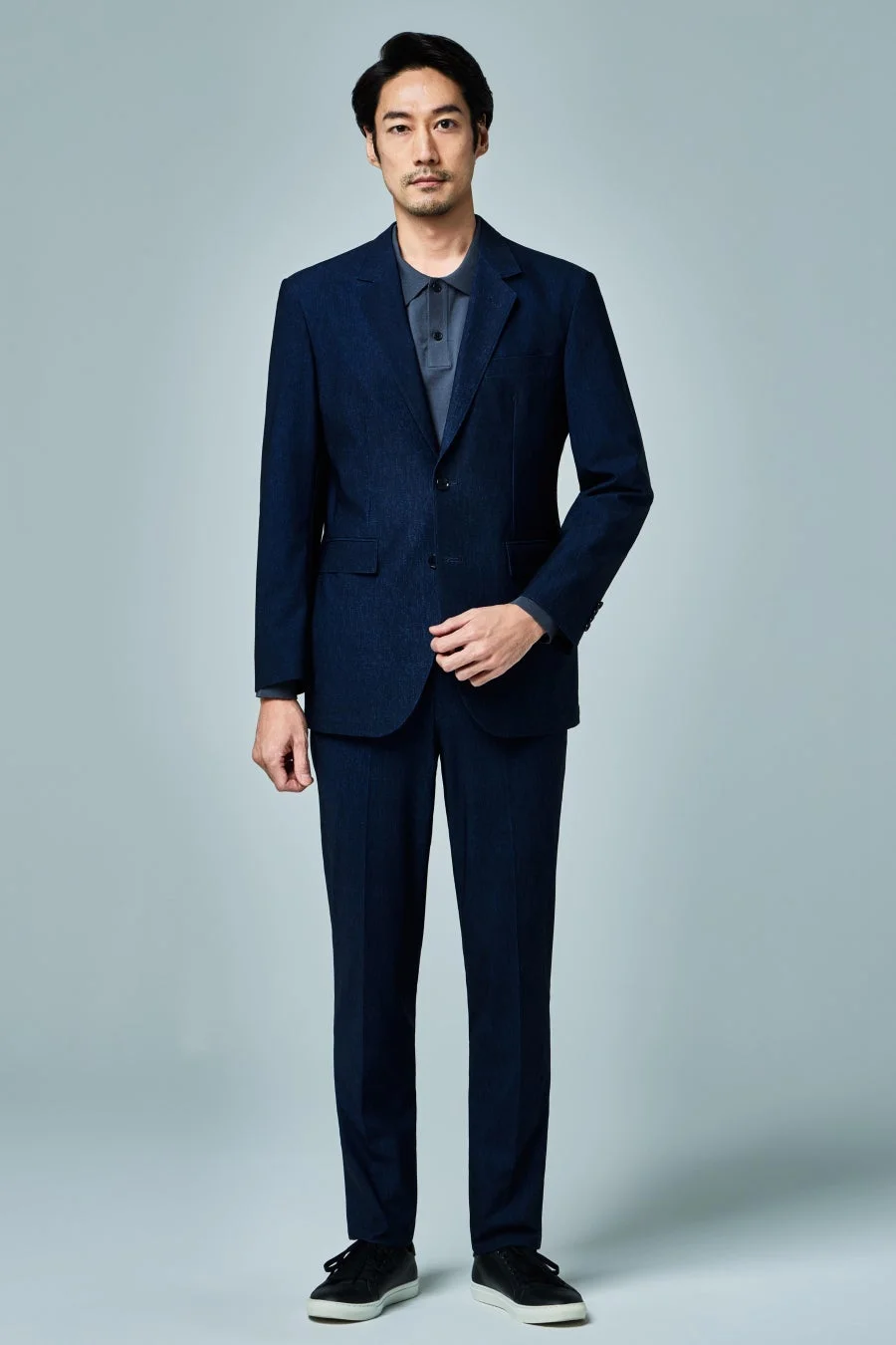 ダークネイビーのスーツとポロシャツを着用した男性