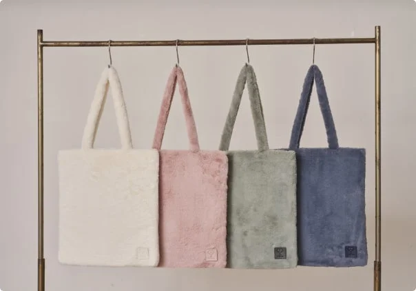 ふわふわとした素材のトートバッグが4色、ハンガーラックに吊るされています。