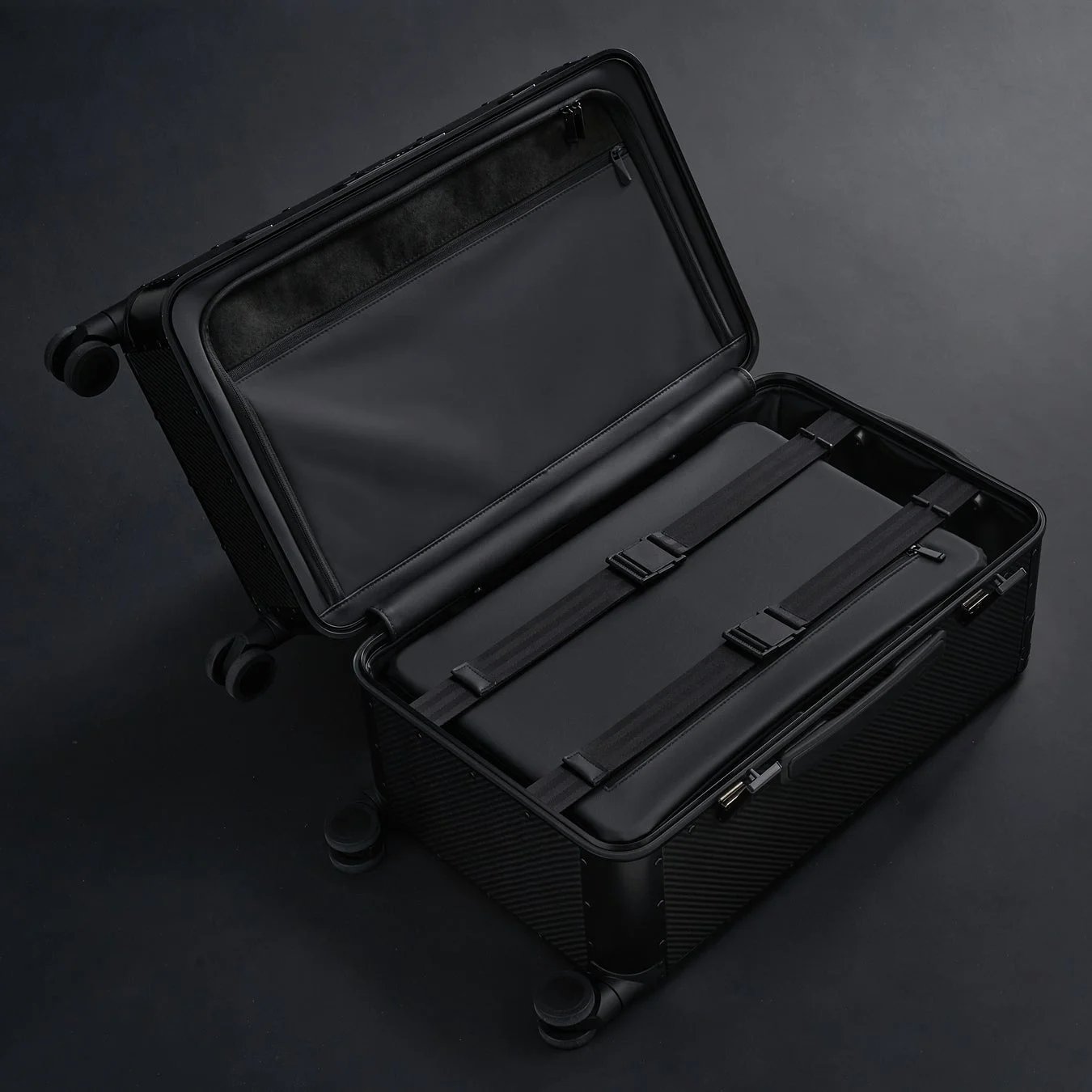 黒いハードケースのスーツケースが開いた状態で写っており、整頓された内部構造と荷物を固定するためのストラップが見えます