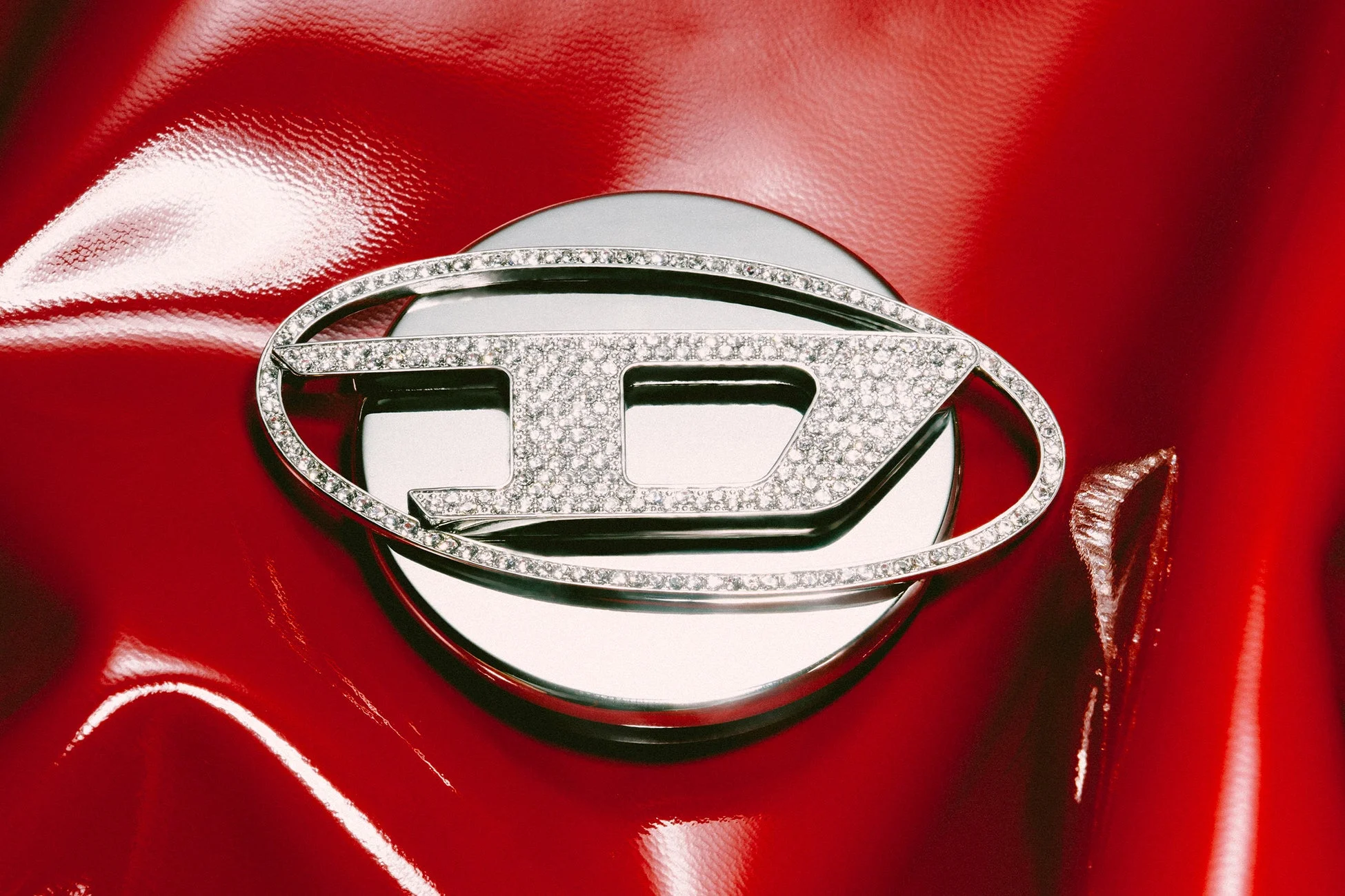 光沢のある赤い背景に、ダイヤモンドがちりばめられたディーゼルの「D」ロゴ