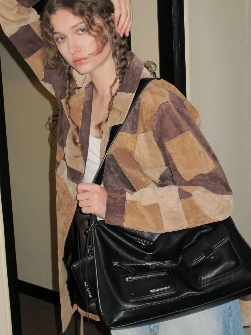 パッチワークジャケットと黒いバッグを持った女性