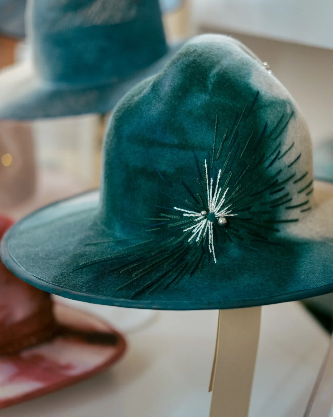 青緑色のフェルトハットに白い刺繍とビーズで星のような装飾