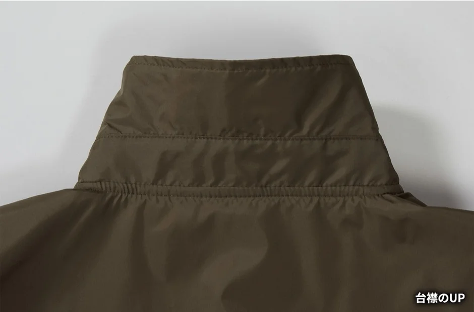 カーキ色のジャケットのスタンドカラー部分をクローズアップした画像です。襟元には複数のステッチが見られ、生地の質感やしわ感がよく分かります。
