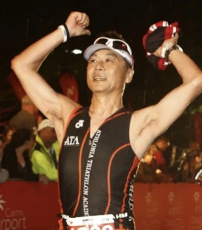 トライアスロンのユニフォームを着た男性が、両腕を上げて勝利を喜んでいる瞬間