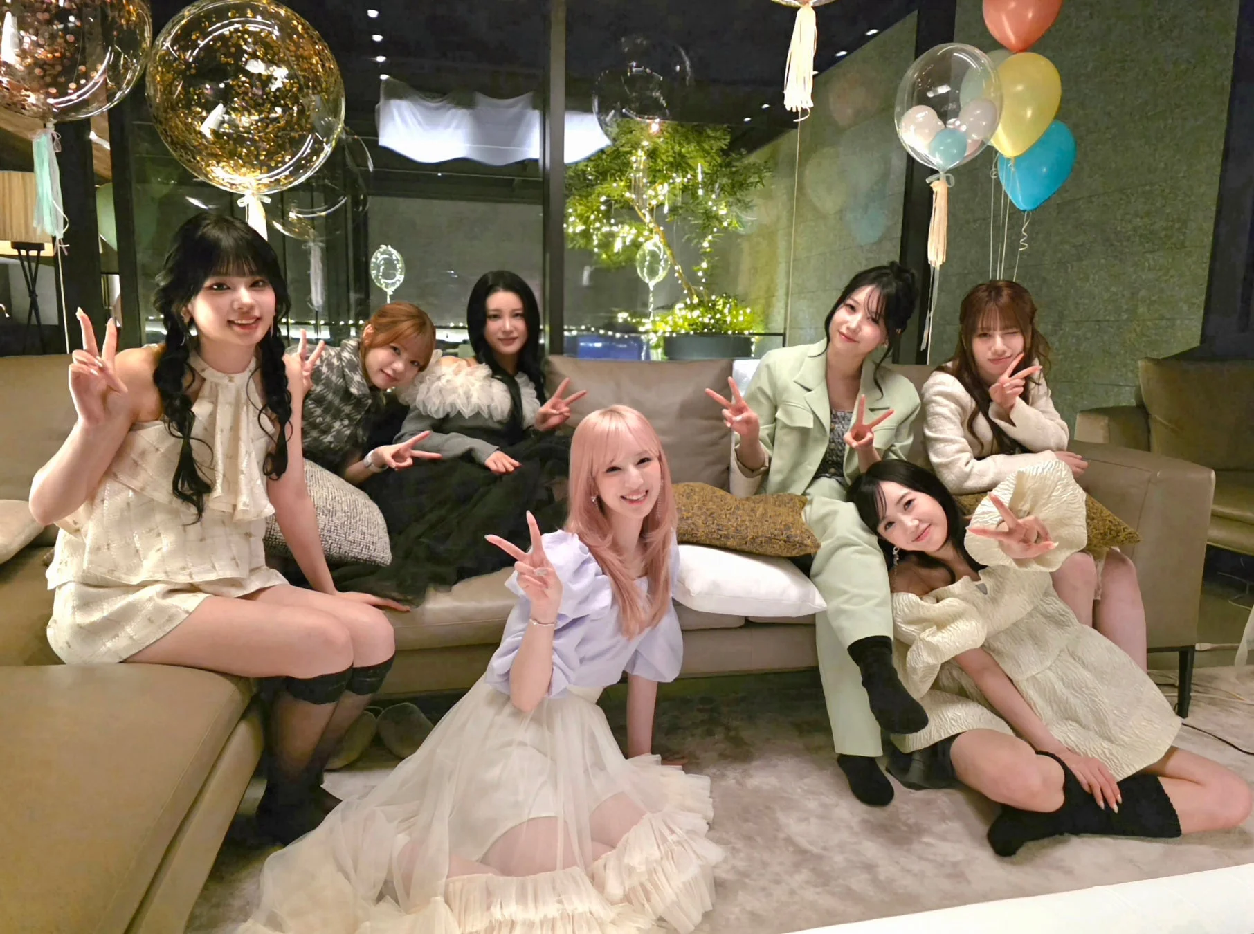 室内で8人の女性たちが集まり、笑顔でピースサインをしながら記念撮影をしている様子です