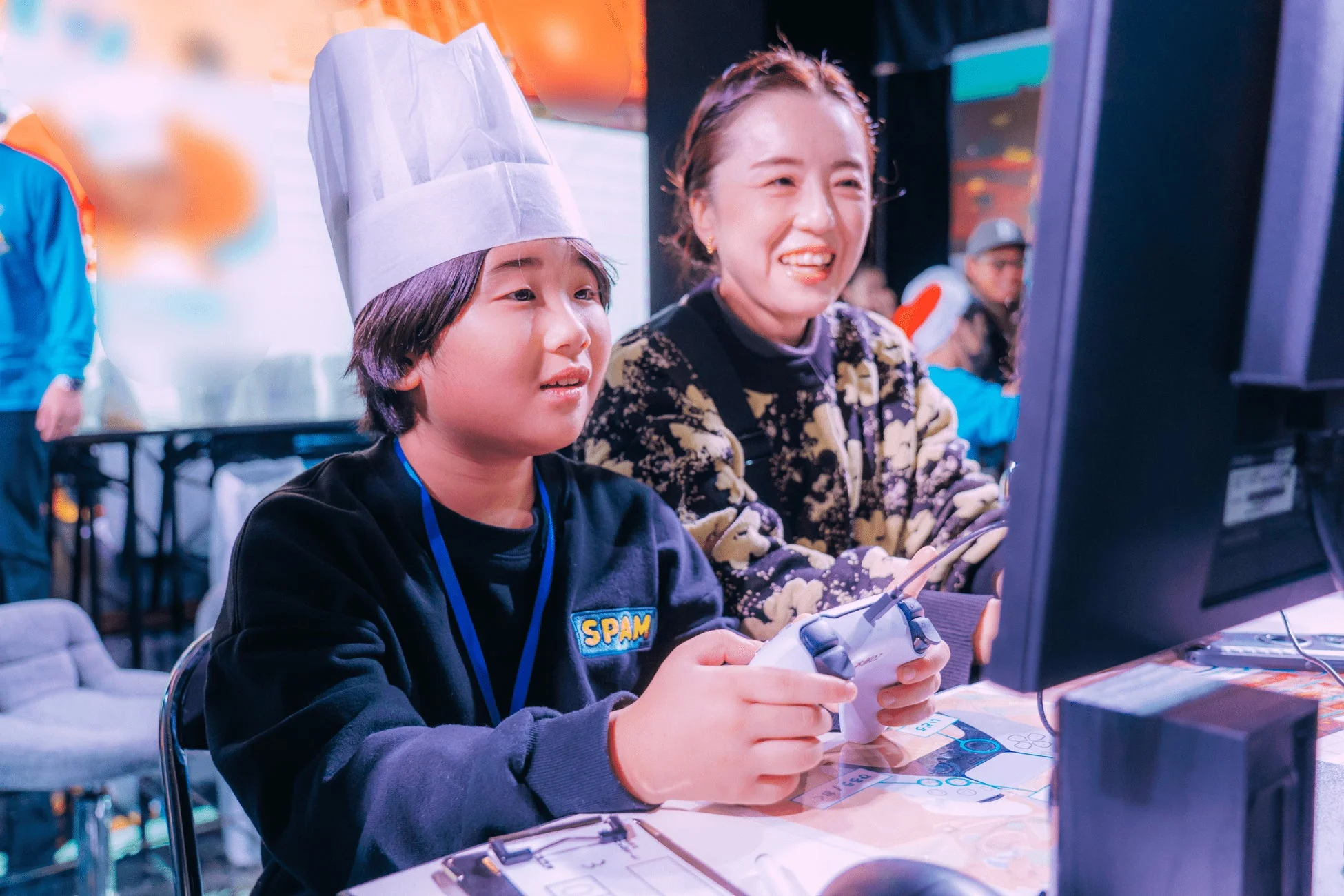 ゲームコントローラーで遊ぶ少年と見守る女性