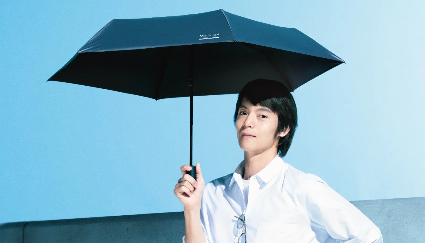 白いシャツを着た男性が黒い傘を差しているWpc. IZAの広告