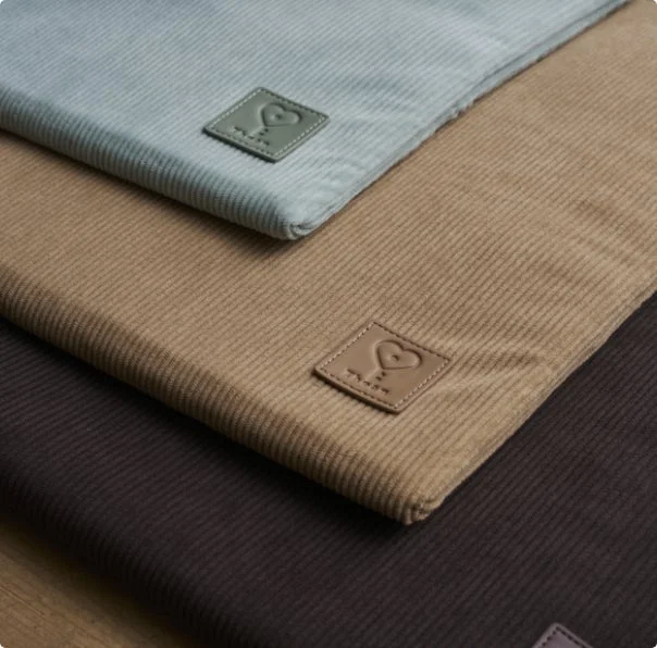 ライトグレー、ベージュ、ダークブラウンの3色のコーデュロイ生地が重なり合って置かれています。