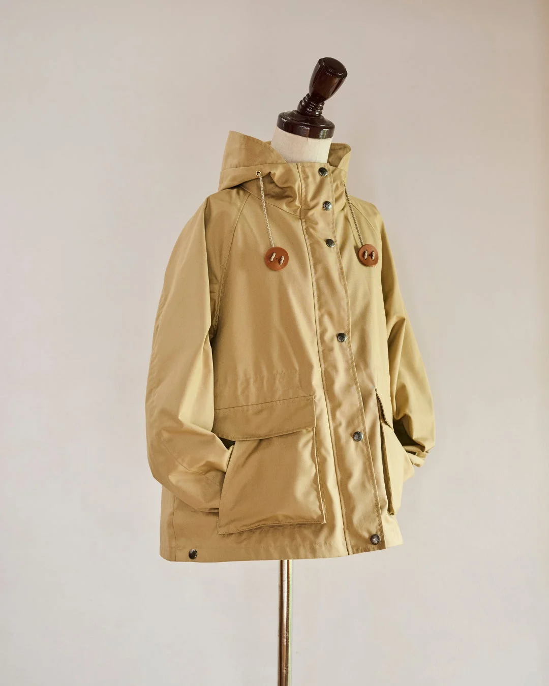 ベージュ色のフード付きジャケットがマネキンに着用されて展示されています。