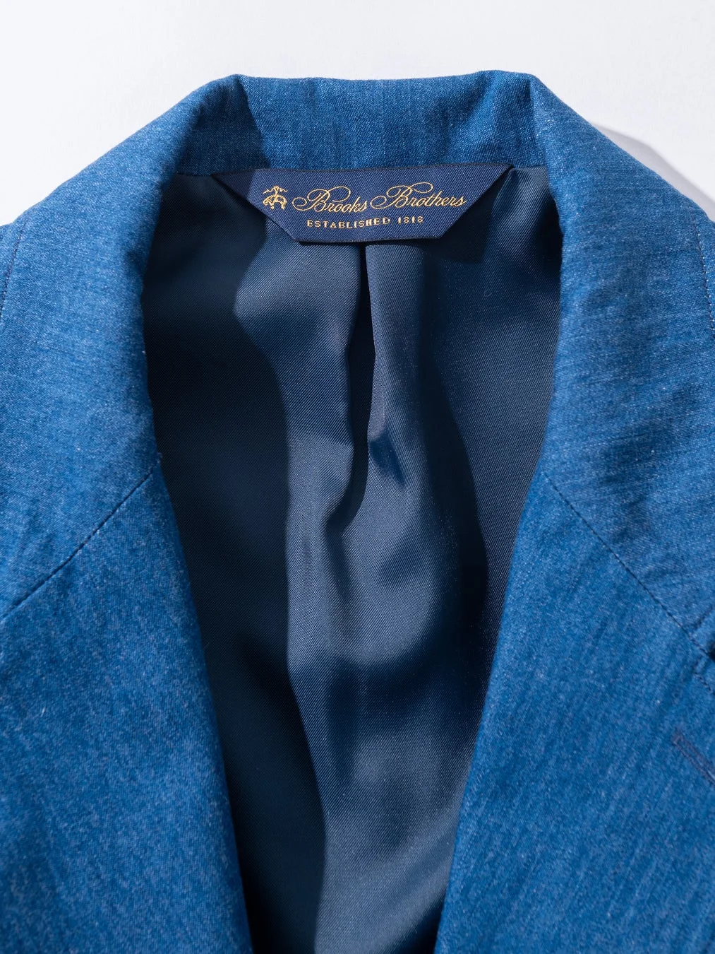 青いジャケットの襟元とブランドタグ