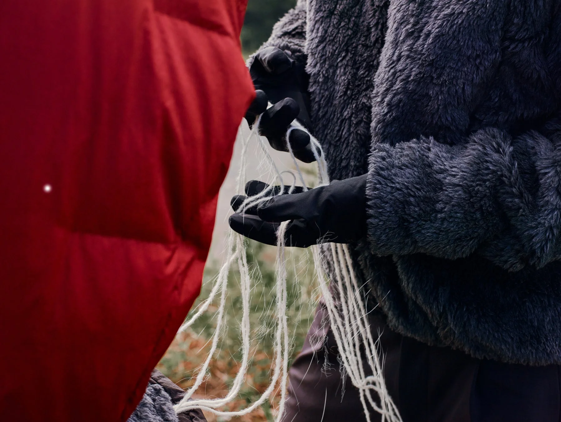 グローブをはめた手が白い糸を操るクローズアップ