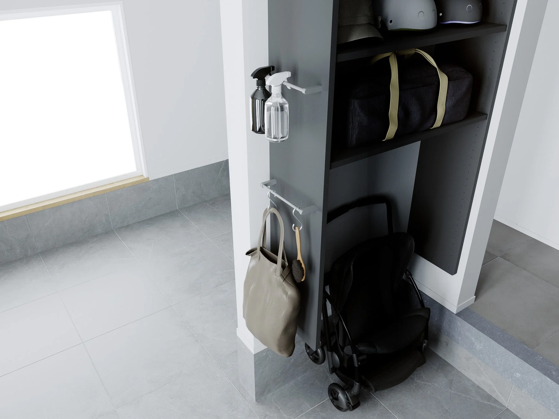 玄関のモダンな収納スペース。ダークグレーの棚にはヘルメットやバッグ、スプレーボトル、トートバッグが整然と置かれ、下には折りたたみベビーカーが収納されている。