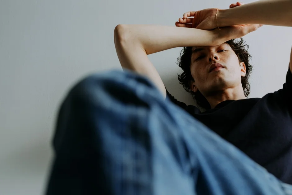 白い壁にもたれて横たわる若い男性