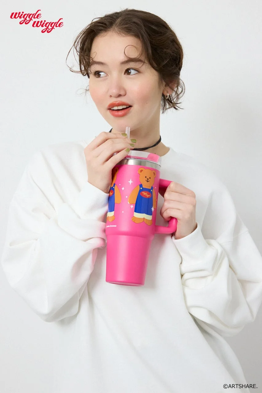 ピンクのクマのイラスト入りタンブラーを持つ女性