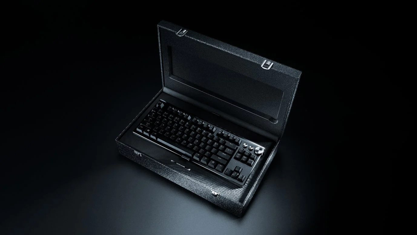 黒い背景に、開かれた黒いケースに収められたメカニカルキーボードの写真です。