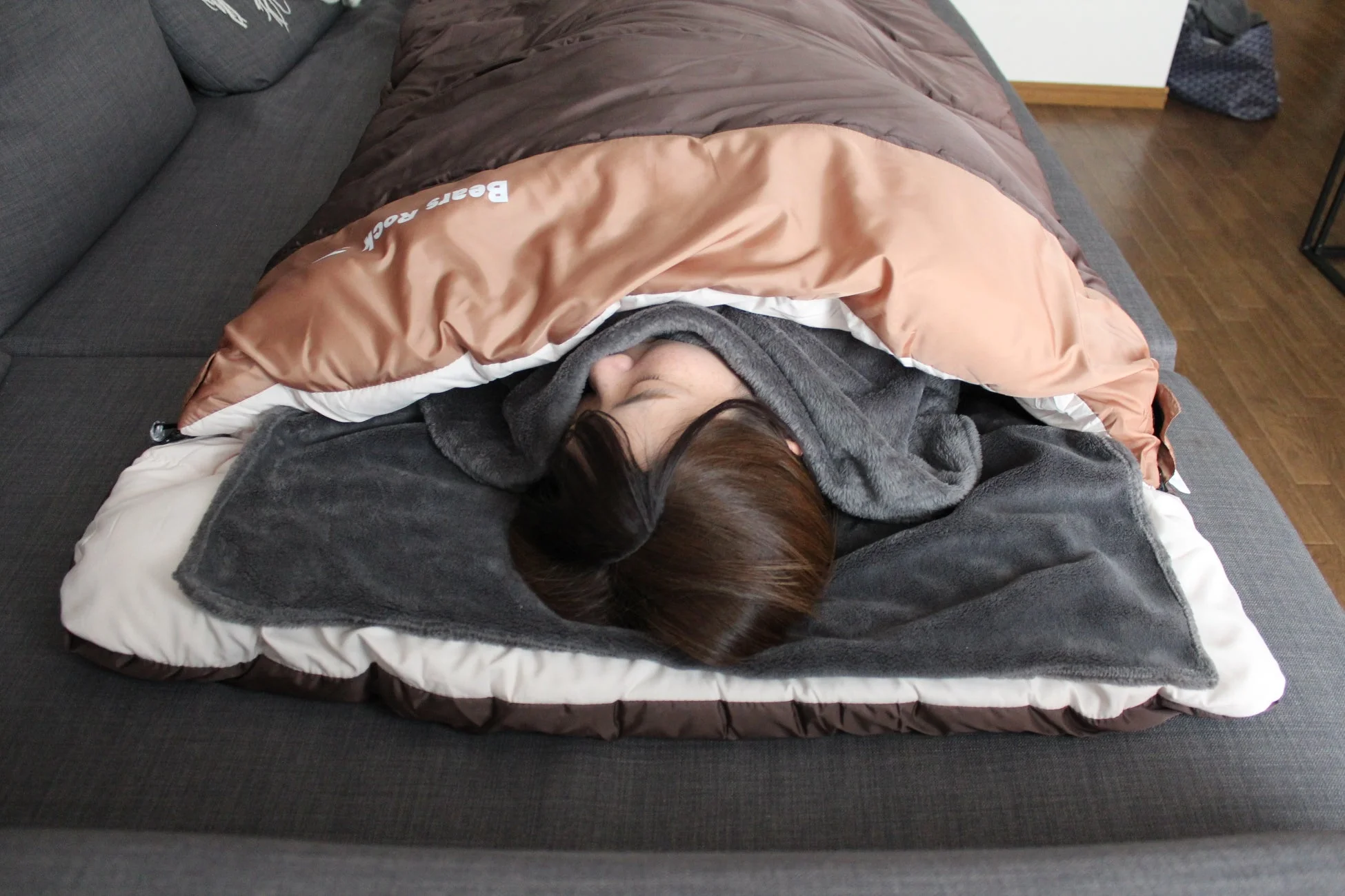 ソファで寝袋に入ってくつろぐ女性