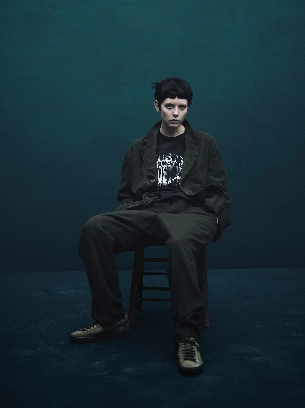 ダークトーンのジャケットとグラフィックTシャツを着用したモデル