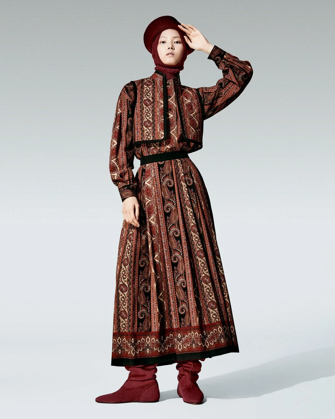 ボルドー系のペイズリー柄のドレスとショートジャケットを着用した女性