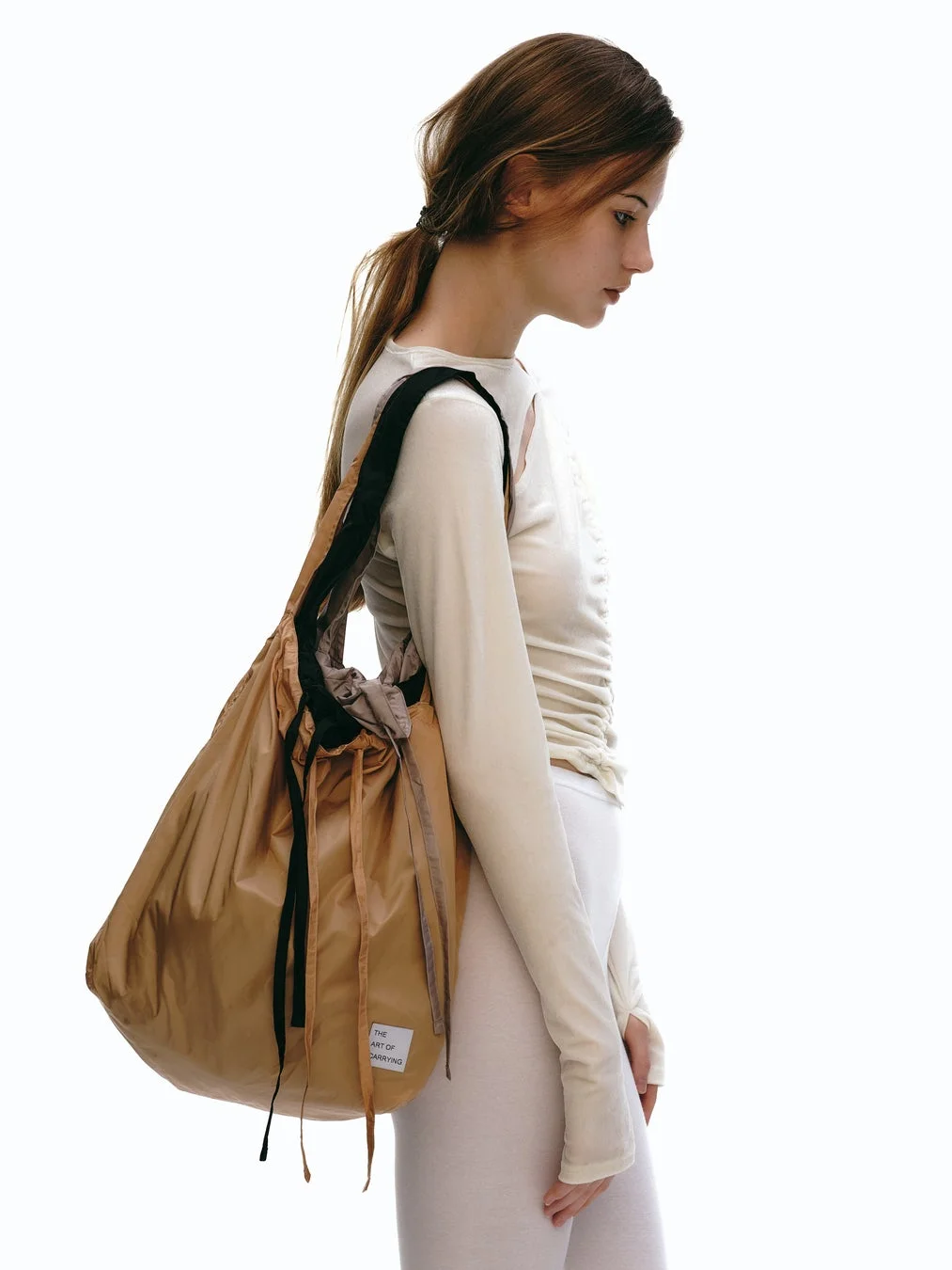 茶色のドローストリングバッグを肩にかけた女性の横顔のポートレート