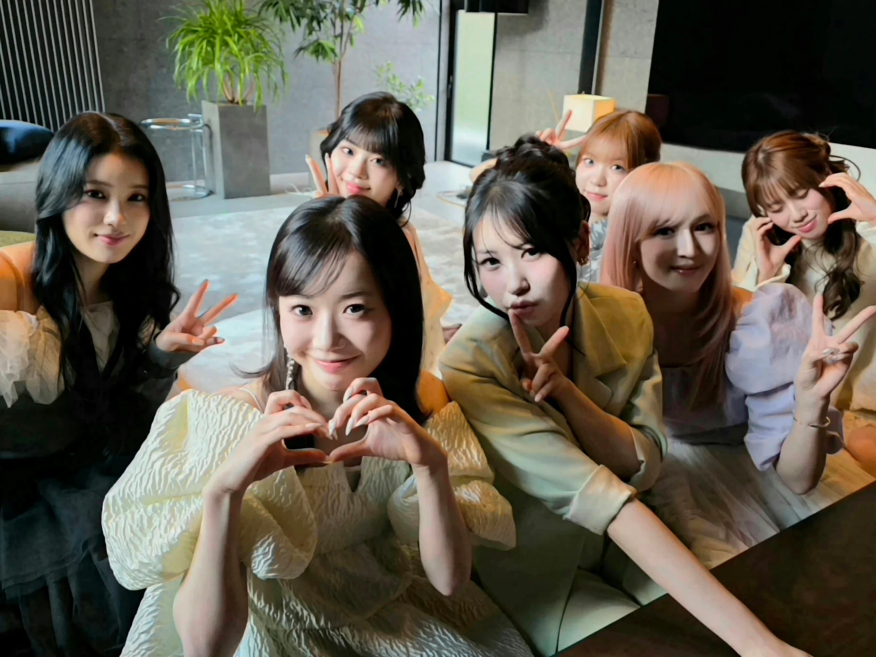 室内で7人の若い女性たちが笑顔で集合写真を撮っている様子
