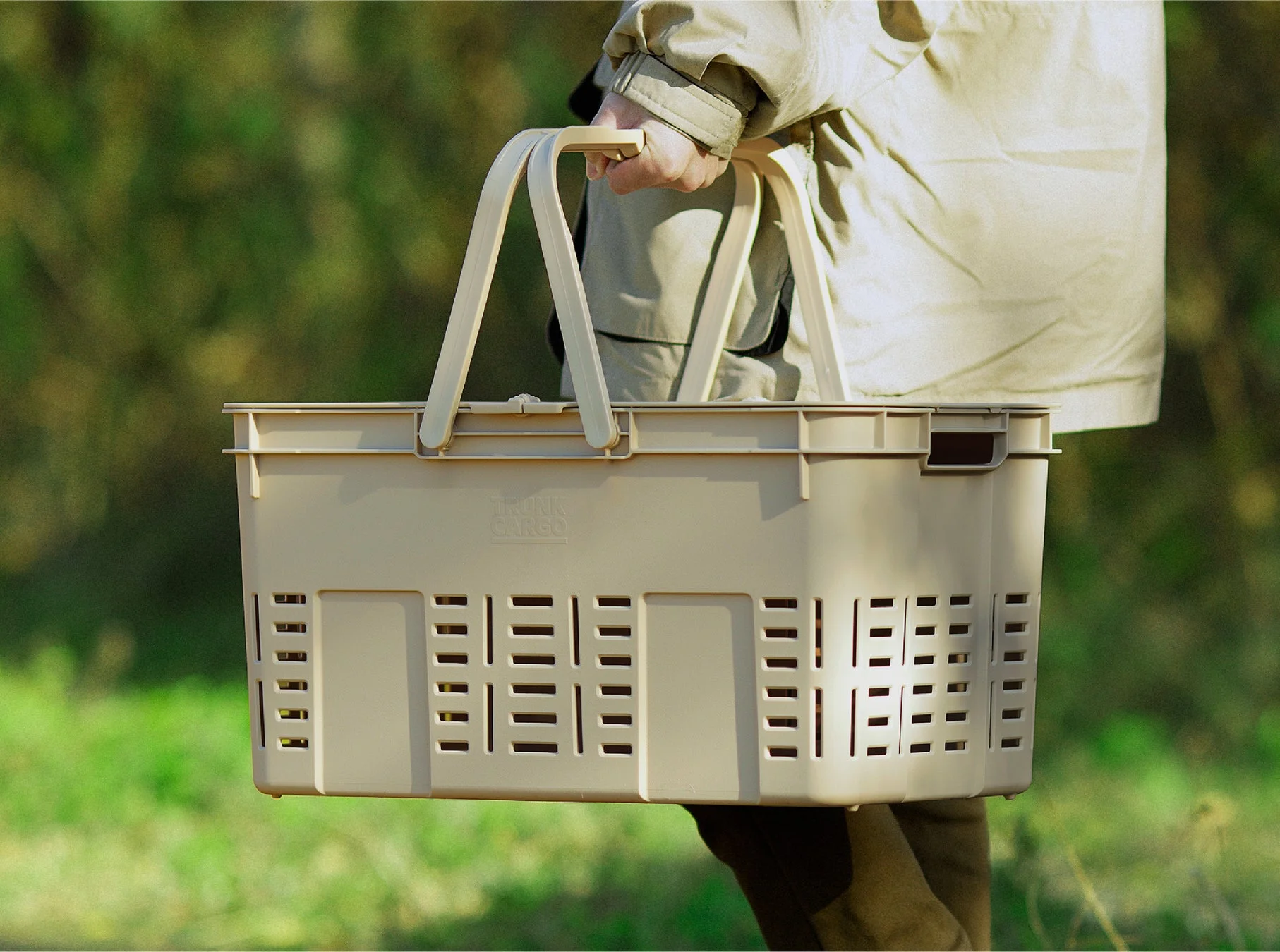 ベージュ色のバスケットを手に持ち屋外を歩く人物