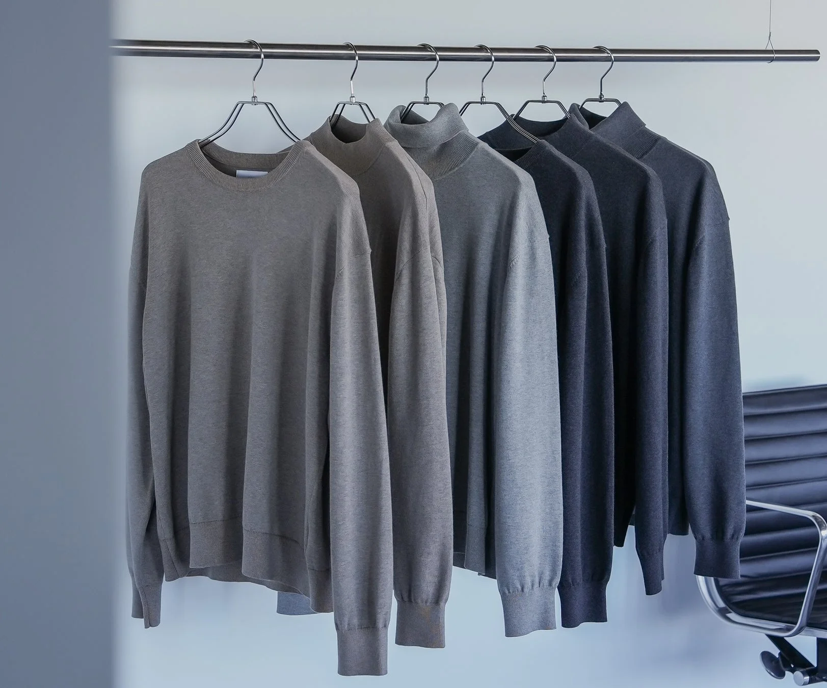 グレー系のニットやセーターがハンガーにかけられ、整然と並べられています