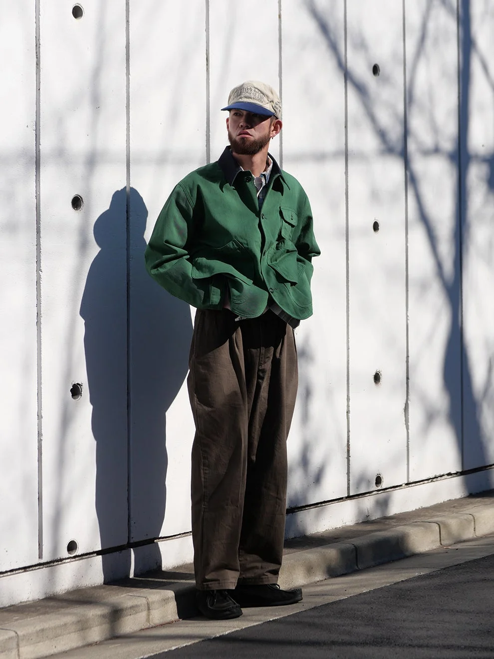 白いコンクリートの壁を背景に立つ男性