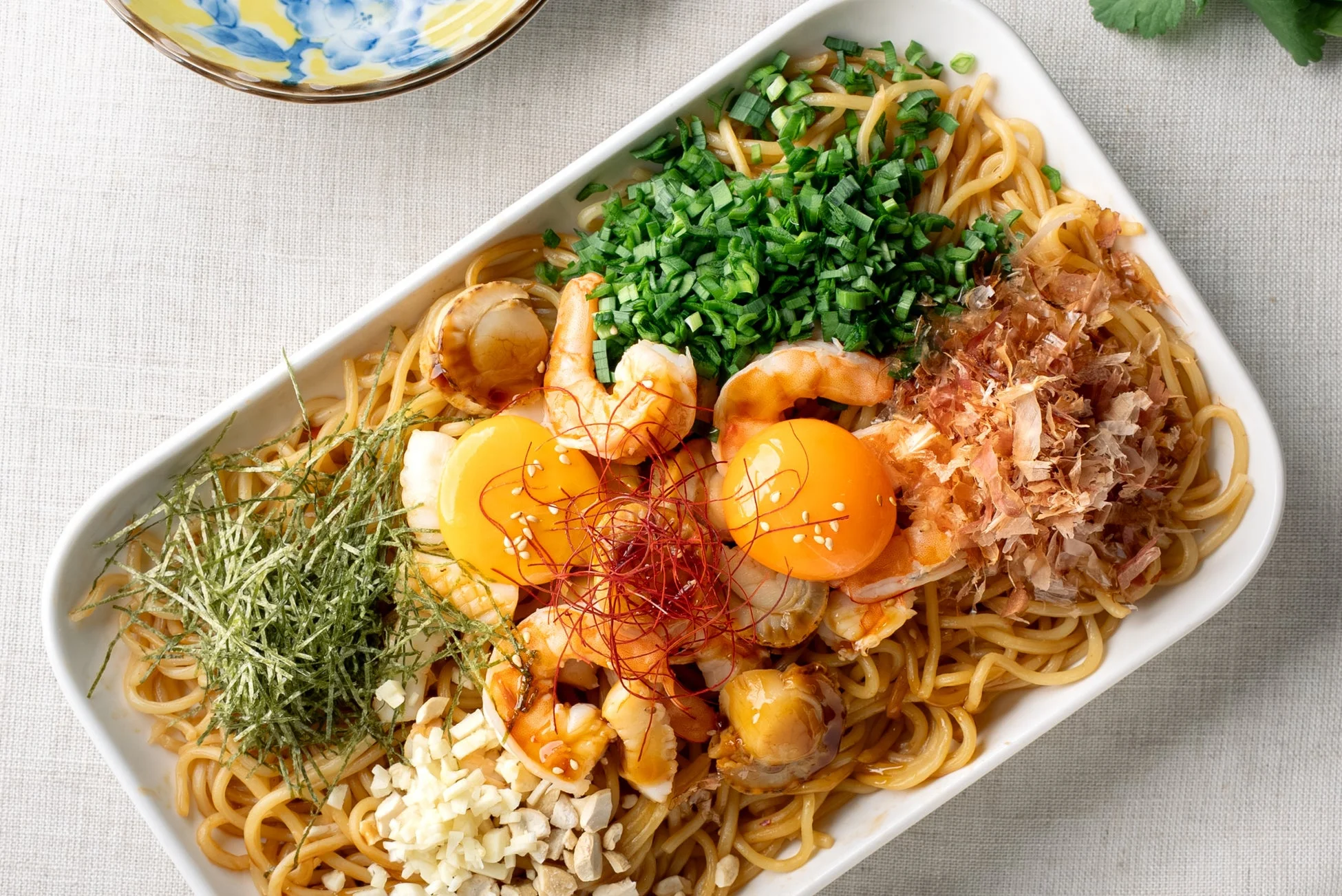 エビやホタテ、卵黄がのった豪華なまぜそばのような麺料理