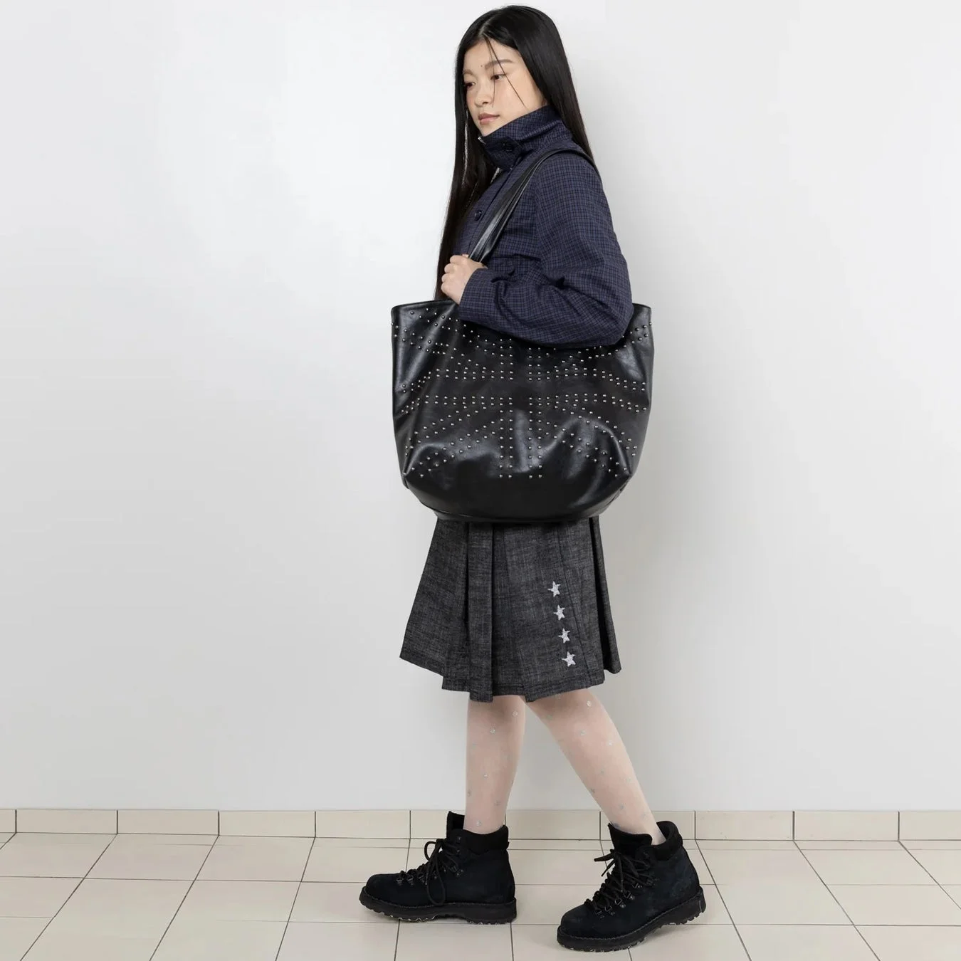 ジャケットとプリーツスカートを着用した女性の全身ファッション