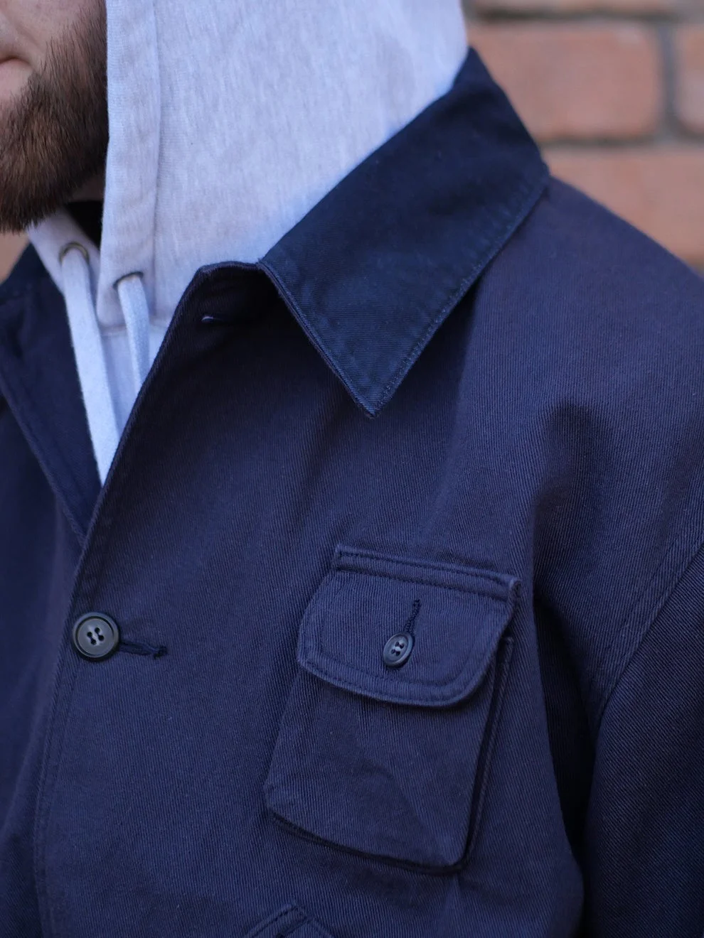 紺色のジャケットとグレーのパーカーを重ね着した男性