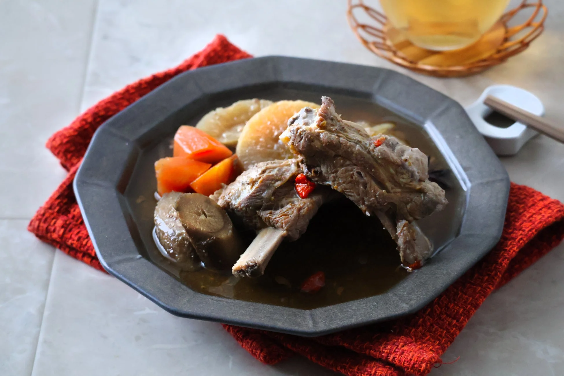 黒い皿に盛られた豚スペアリブと根菜の煮込み料理