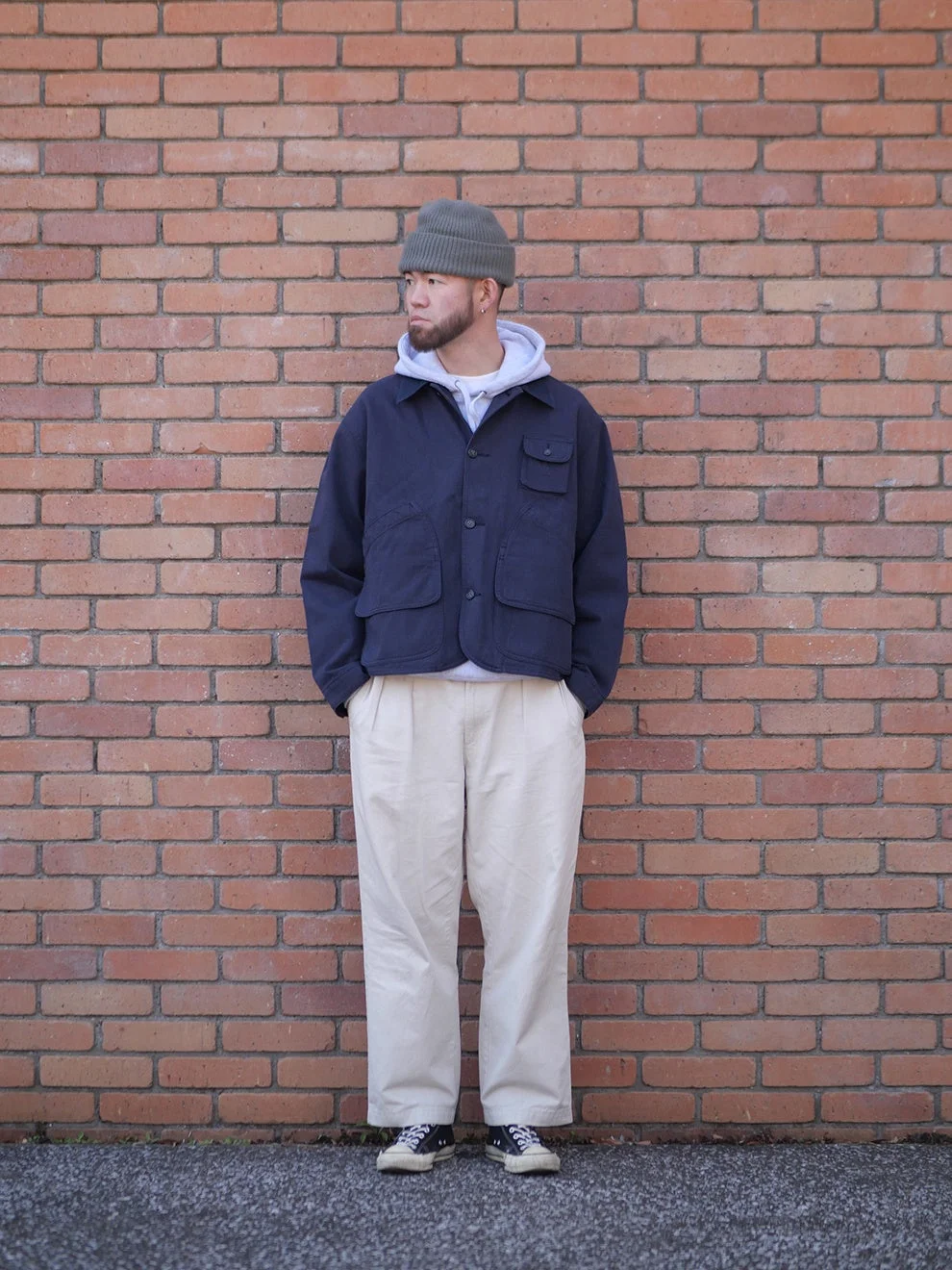 レンガの壁を背景に立つ男性の全身ショット